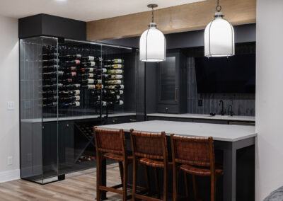 Omaha Home, Kitchen, Bathroom and Basement Remodeling - Modern kitchen with a glass-enclosed wine cellar, pendant lighting, and stylish bar stools.