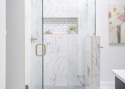 Omaha Home, Kitchen, Bathroom and Basement Remodeling - A modern bathroom featuring a luxurious walk-in shower with marble walls, gold fixtures, and a glass door.